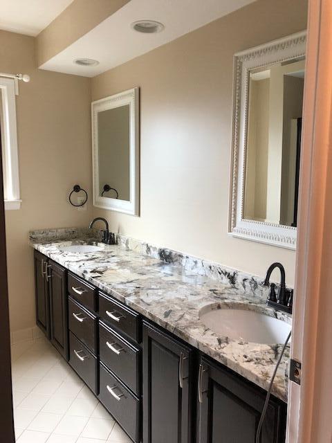 full bath featuring double vanity, tile patterned floors, and a sink