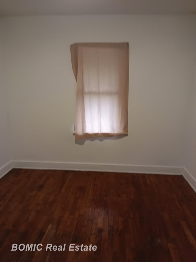 unfurnished room featuring baseboards and dark wood-style flooring