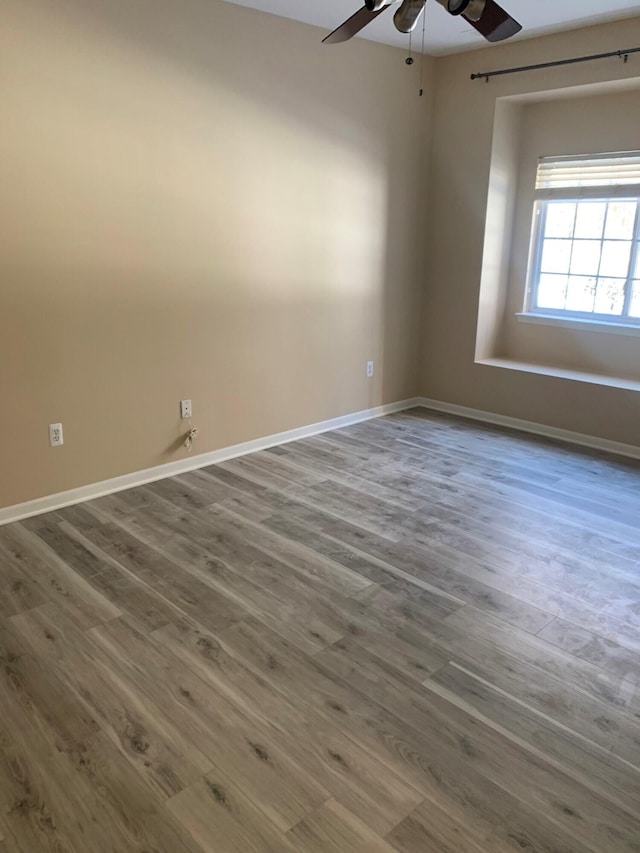 empty room featuring baseboards, ceiling fan, and wood finished floors