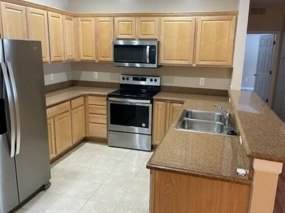 kitchen featuring a sink, light brown cabinets, stainless steel appliances, a peninsula, and visible vents