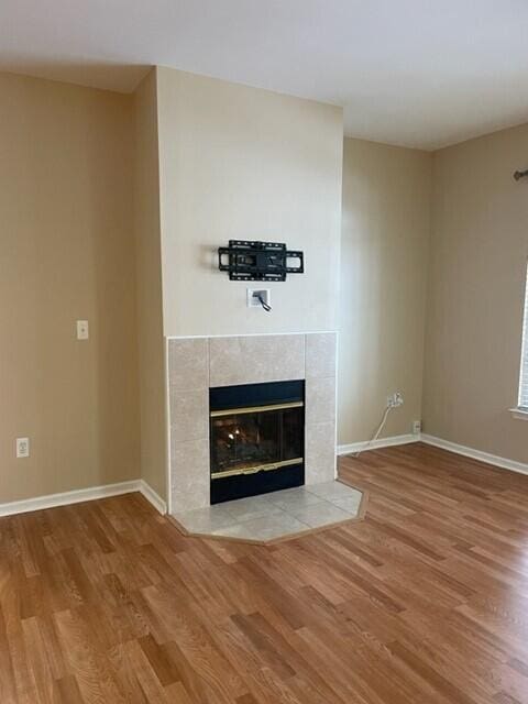 unfurnished living room featuring baseboards, a fireplace, and wood finished floors
