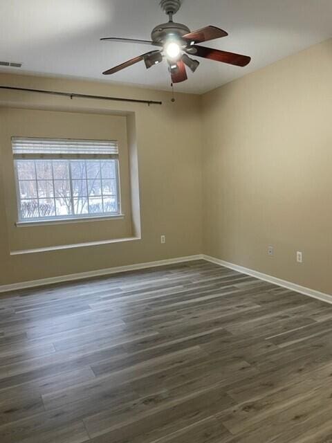 unfurnished room featuring a ceiling fan, baseboards, visible vents, and wood finished floors