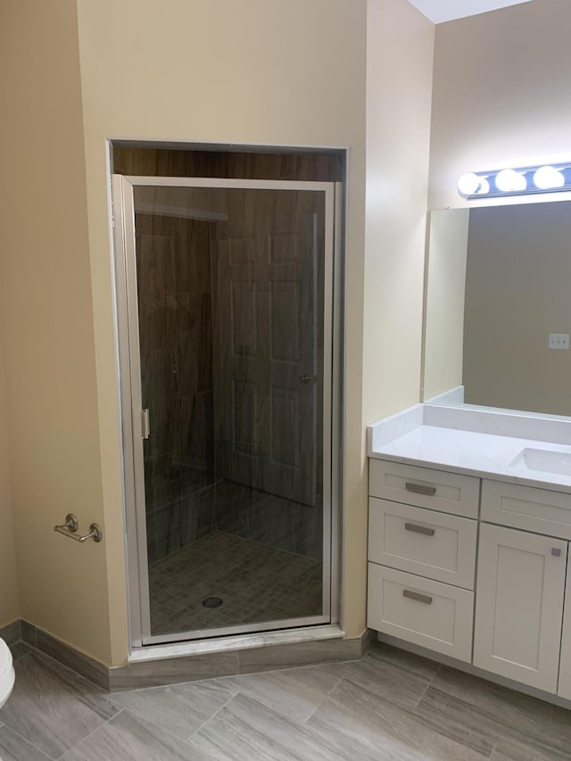 full bath featuring vanity, baseboards, and a shower stall