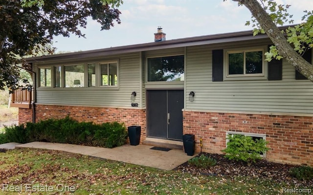 split foyer home with a chimney and brick siding