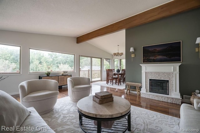 living area featuring a textured ceiling, lofted ceiling with beams, wood finished floors, and a notable chandelier