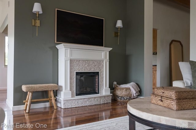 living room with baseboards, a fireplace with raised hearth, and wood finished floors