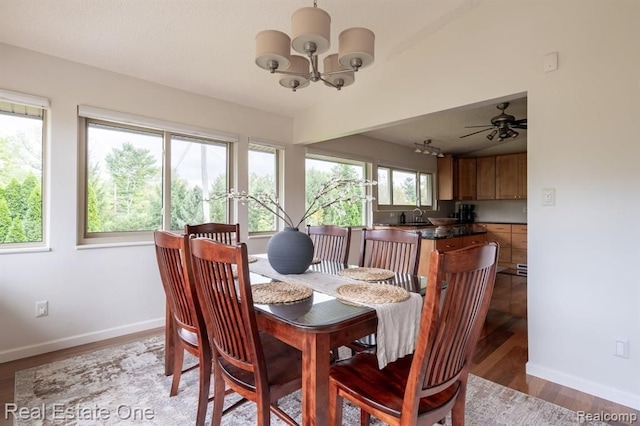 dining room featuring baseboards, light wood finished floors, and ceiling fan with notable chandelier
