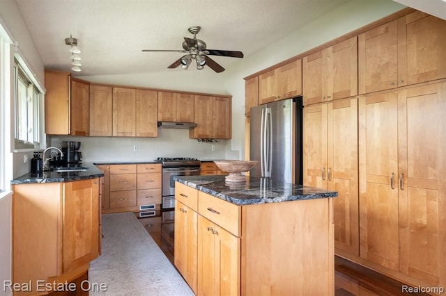 kitchen with a sink, dark stone countertops, stainless steel appliances, a ceiling fan, and vaulted ceiling
