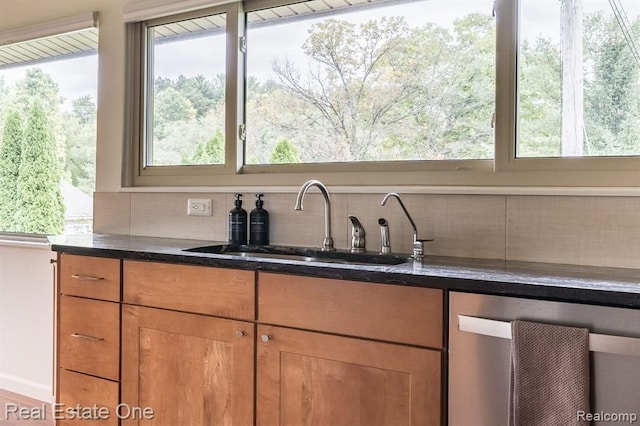 kitchen featuring a sink, brown cabinetry, dark stone countertops, tasteful backsplash, and stainless steel dishwasher