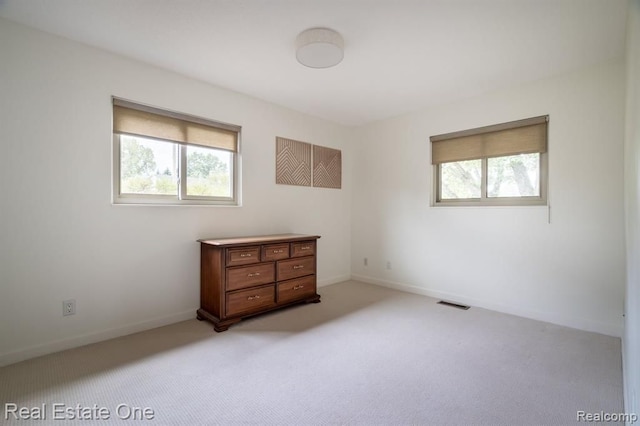 unfurnished bedroom with light colored carpet, baseboards, and multiple windows