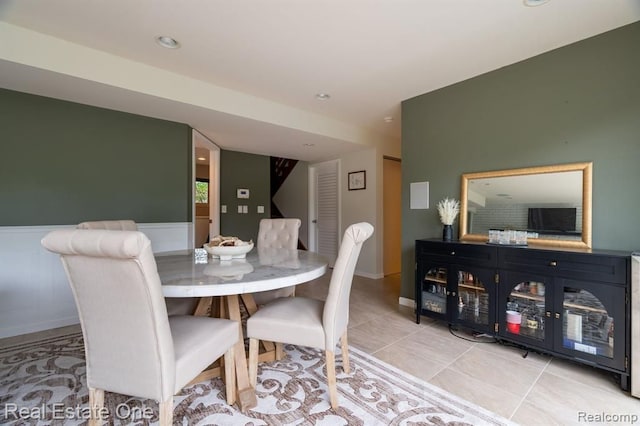 dining space with recessed lighting, light tile patterned floors, and a wainscoted wall