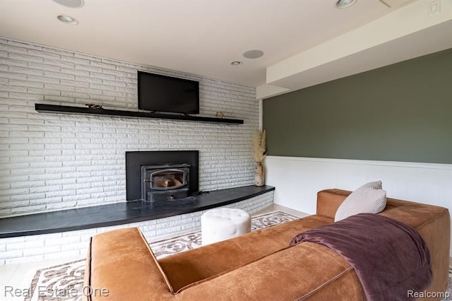 living room with recessed lighting, a wood stove, and a wainscoted wall