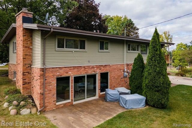 back of property with a lawn, brick siding, and a chimney