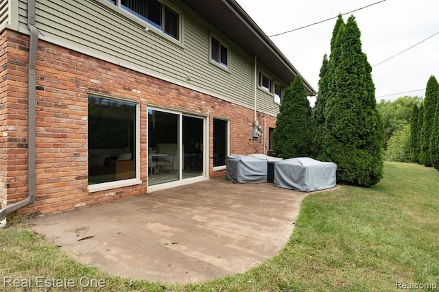 rear view of house featuring a yard and brick siding