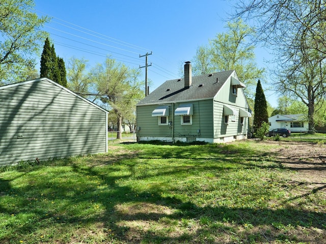 back of property with a chimney and a lawn