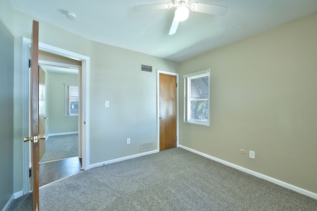 unfurnished bedroom with dark carpet, baseboards, and ceiling fan