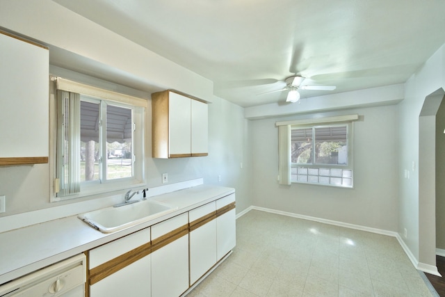 kitchen featuring a sink, dishwasher, baseboards, and light countertops