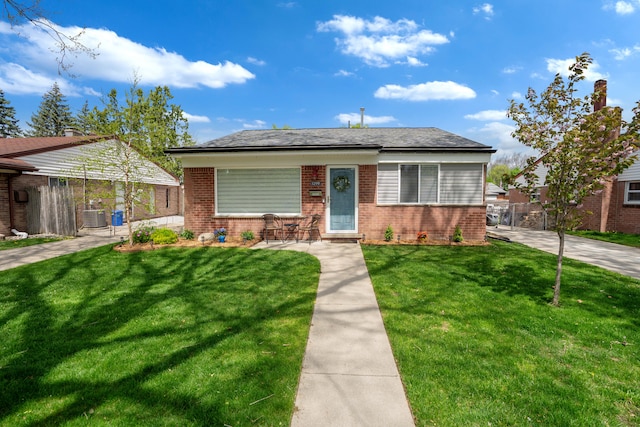 bungalow-style house featuring brick siding, central AC, and a front yard
