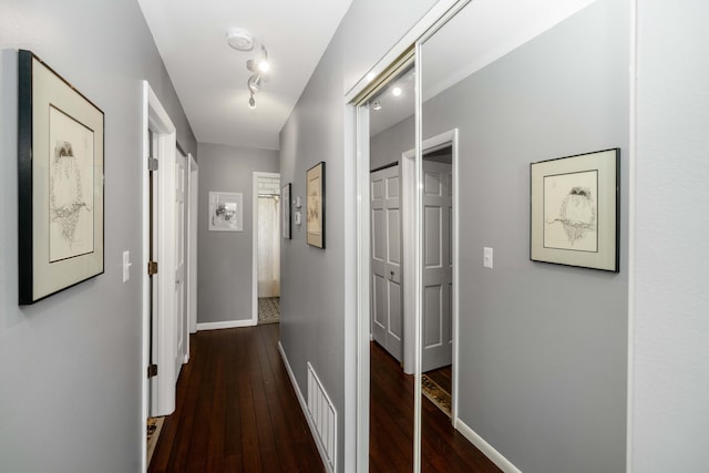 corridor with visible vents, baseboards, and hardwood / wood-style flooring