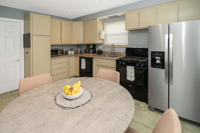 kitchen with light countertops, a sink, appliances with stainless steel finishes, and cream cabinetry
