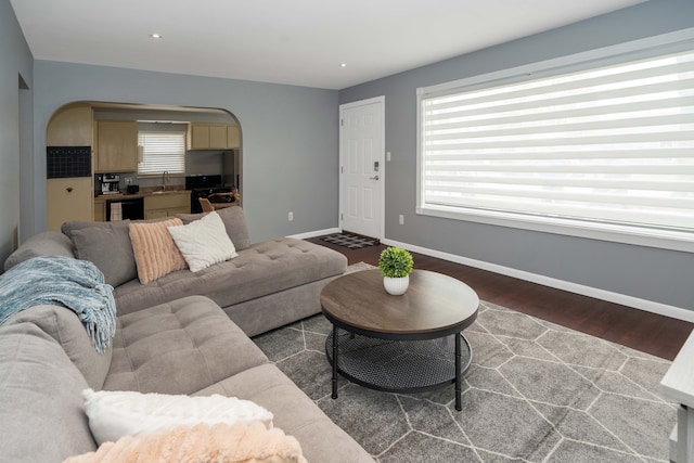 living area with beverage cooler, arched walkways, baseboards, and wood finished floors