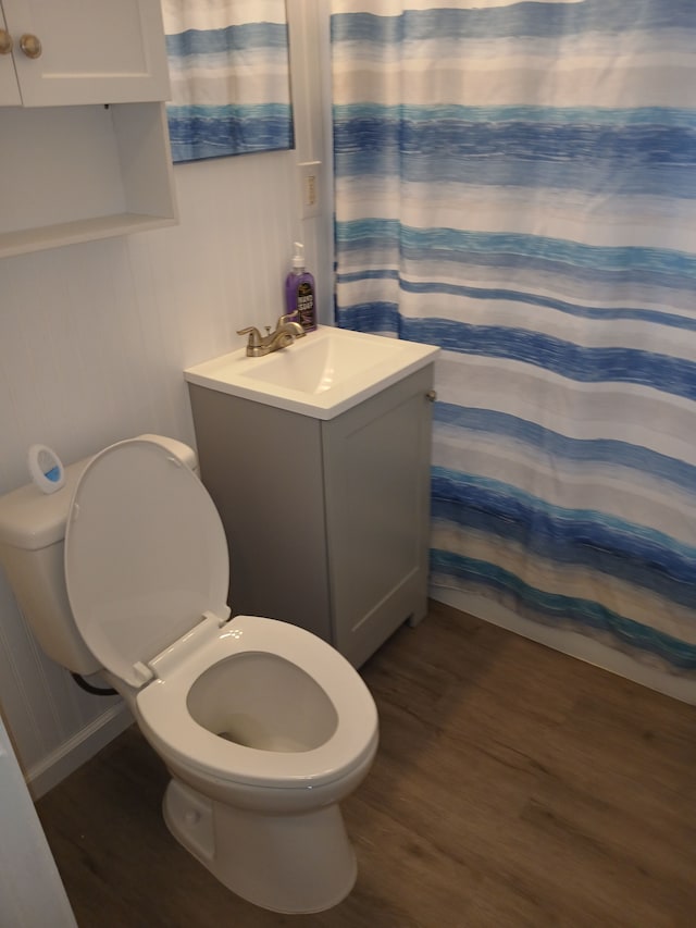 full bath with curtained shower, vanity, toilet, and wood finished floors
