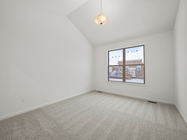 empty room with baseboards, visible vents, vaulted ceiling, and light colored carpet