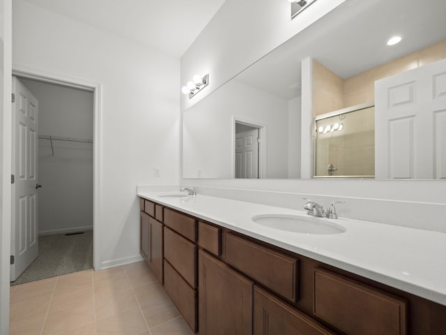 bathroom with double vanity, a spacious closet, a shower stall, and a sink
