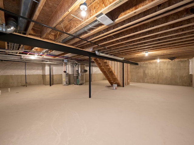 unfinished below grade area featuring stairs and water heater