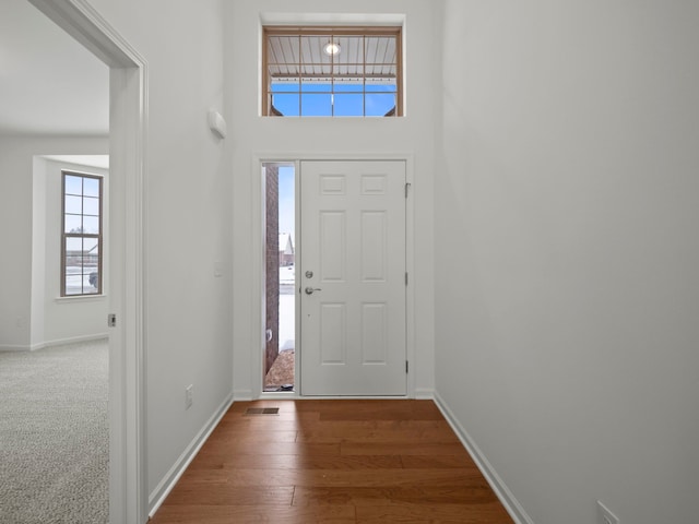 foyer featuring baseboards, visible vents, and wood finished floors