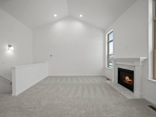 unfurnished living room featuring visible vents, light colored carpet, lofted ceiling, and a fireplace