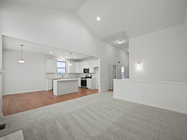 unfurnished living room with light carpet, baseboards, high vaulted ceiling, recessed lighting, and a sink