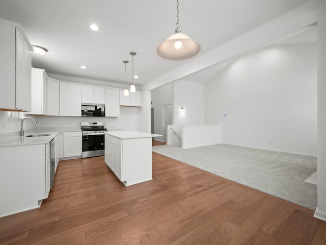 kitchen featuring appliances with stainless steel finishes, a sink, light countertops, open floor plan, and recessed lighting
