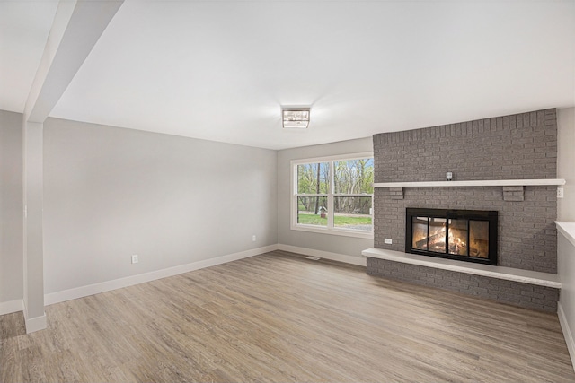 785 Maple Dr, Columbiaville, MI 48421 - unfurnished living room featuring wood finished floors, baseboards, and a fireplace