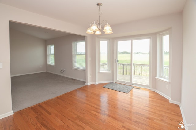 doorway featuring baseboards, light wood-style flooring, and a chandelier