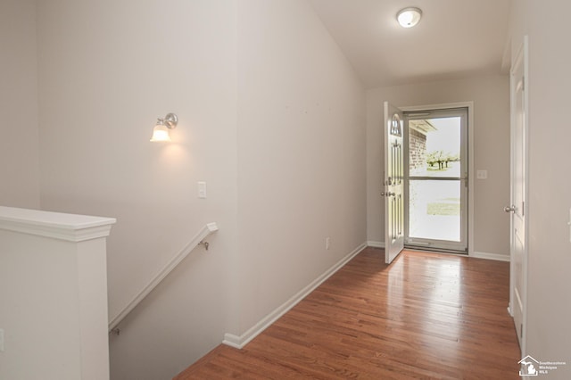 doorway to outside featuring baseboards, vaulted ceiling, and wood finished floors