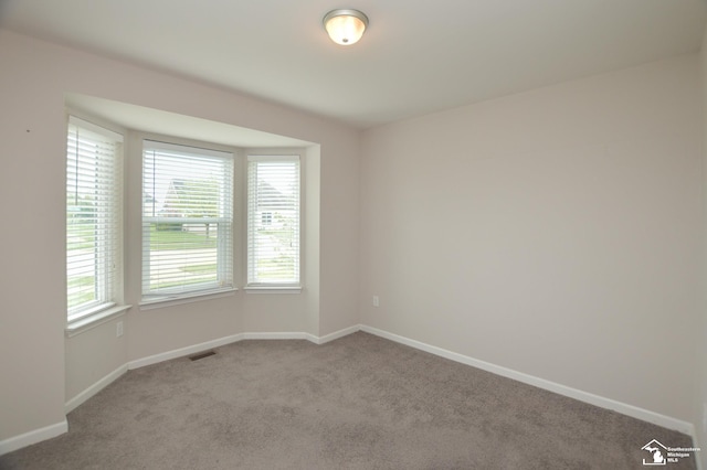 empty room with carpet flooring, baseboards, and visible vents