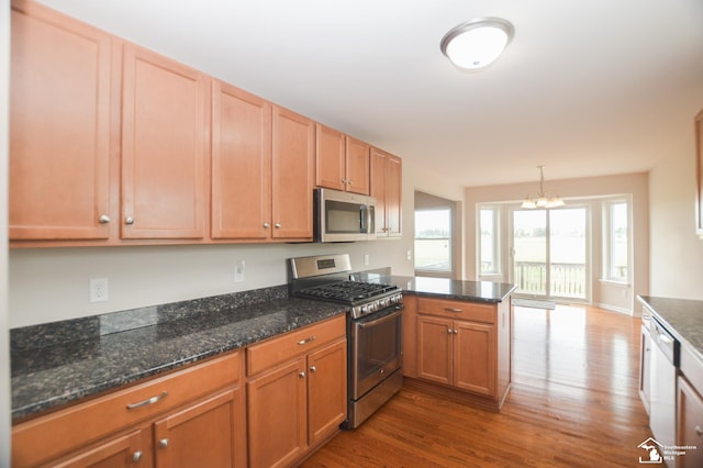 kitchen featuring a peninsula, dark stone countertops, stainless steel appliances, and dark wood-style flooring