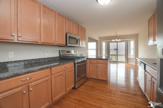 kitchen with stainless steel appliances, a peninsula, light wood-style flooring, and a chandelier