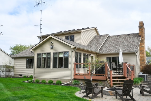 back of house with a lawn, a patio area, a shingled roof, a wooden deck, and a fire pit