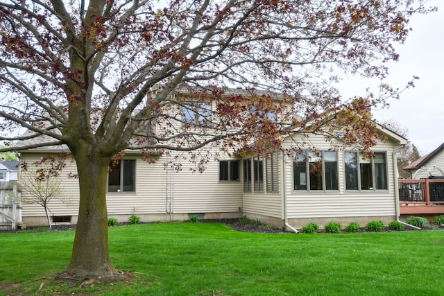 rear view of property featuring a lawn and a deck