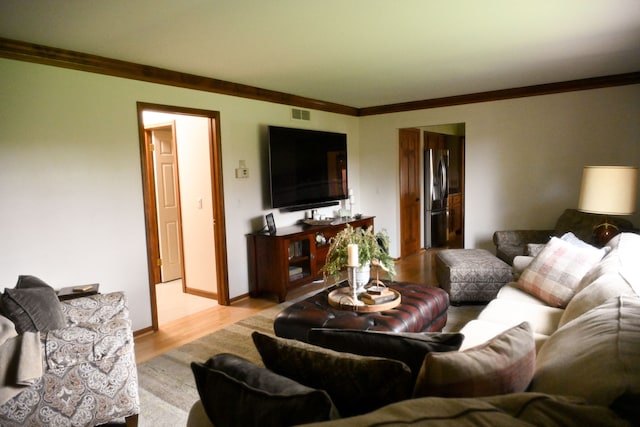living area featuring ornamental molding, visible vents, and light wood-type flooring