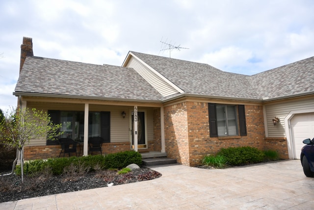 single story home with a chimney, brick siding, a shingled roof, concrete driveway, and a porch