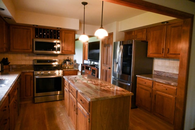 kitchen with appliances with stainless steel finishes, a center island, brown cabinets, and dark wood-style floors
