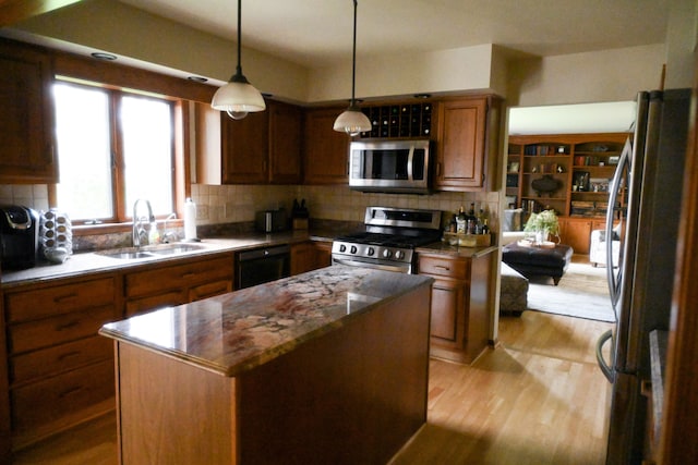 kitchen featuring a sink, a kitchen island, stainless steel appliances, tasteful backsplash, and light wood-type flooring