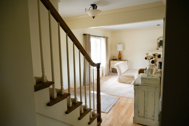 staircase featuring wood finished floors and ornamental molding