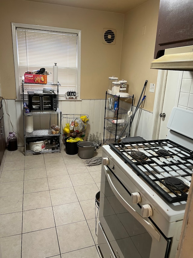 15758 Hubbell St, Detroit, MI 48227 - kitchen featuring white range with gas stovetop, wainscoting, and light tile patterned flooring