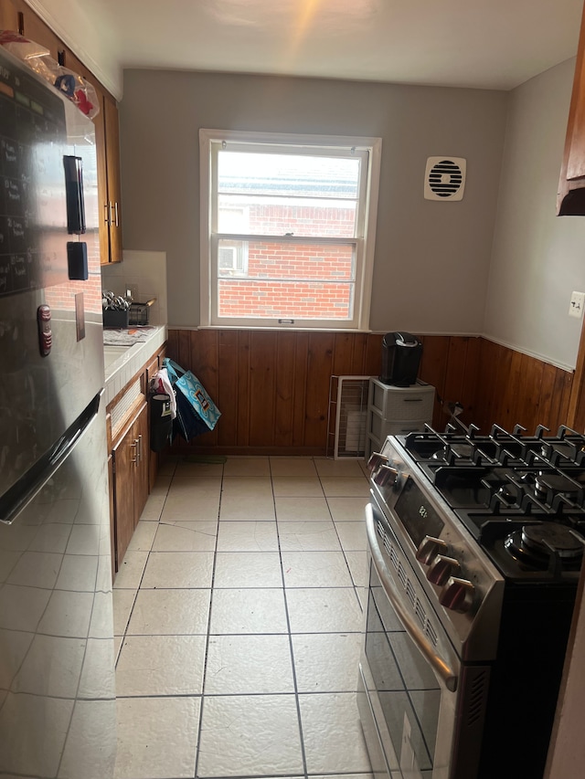 15758 Hubbell St, Detroit, MI 48227 - kitchen with appliances with stainless steel finishes, a wainscoted wall, light countertops, wooden walls, and light tile patterned floors