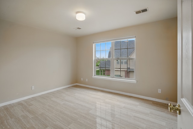 unfurnished room featuring baseboards, light wood finished floors, and visible vents