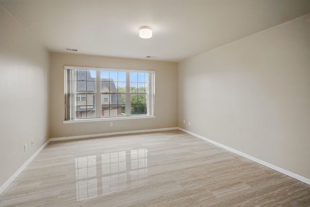 unfurnished room featuring light wood finished floors, baseboards, and visible vents